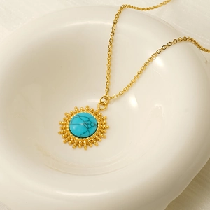 Macro shot of vintage turquoise sunflower pendant necklace on a white ceramic dish