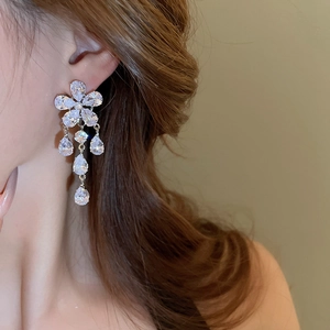 Detail of silver drop earrings featuring zircon flower petals and crystal tassels on model
