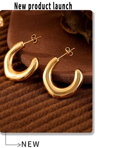 Macro shot of 18k gold plated chunky C-shaped irregular earrings on brown fabric