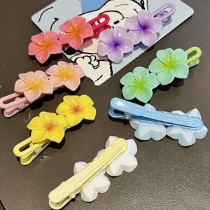 Colorful plumeria flower duckbill hair clips for girls set on a textured grey background