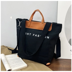 Detail of black canvas tote bag with brown leather handles and GHT FASHION print
