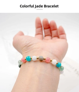 Dettaglio del bracciale con pietre multicolori e perle dorate indossato su un polso