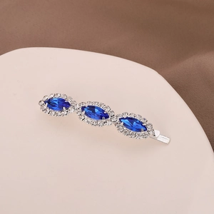 Detail of silver hair clip with three oval blue crystals surrounded by clear rhinestones