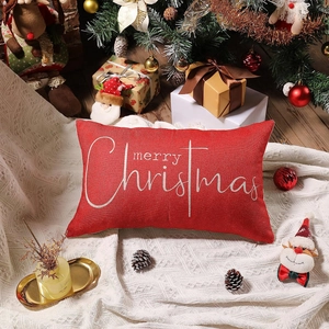 Close-up of red linen Christmas lumbar pillow featuring white Merry Christmas script on knit rug