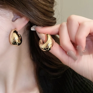 Gros plan de boucles d'oreilles en C dorées et polies en forme de larme sur un mannequin