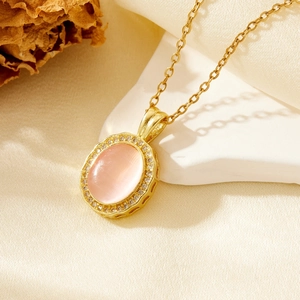 Macro detail of gold teardrop pendant necklace with pink gemstone and pavé diamonds