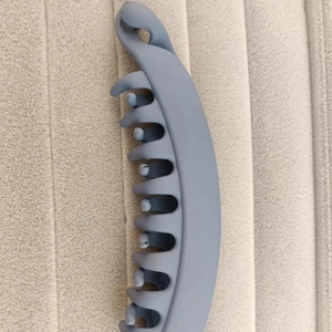 Vertical matte grey banana hair clip for ponytail styling on a textured beige background