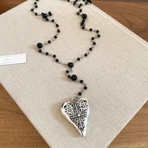 Détail du collier avec pendentif cœur et croix posé sur un livre inspirant
