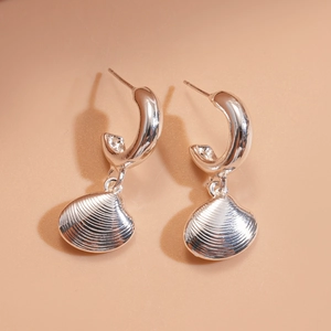 Detail of silver shell pendant earrings with sparkling zircons on warm pink backdrop