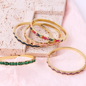 Detail of wave-edged 18k gold-plated bangles with multi-colored baguette-cut crystals