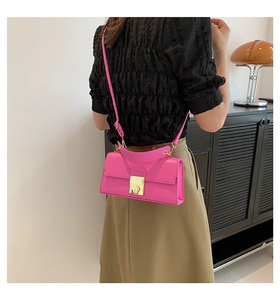 Detail of the pink leather crossbody bag with gold metal clasp on a model's shoulder