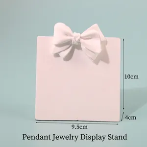 White resin jewelry display stand with bow detail showing 9.5cm x 10cm dimensions