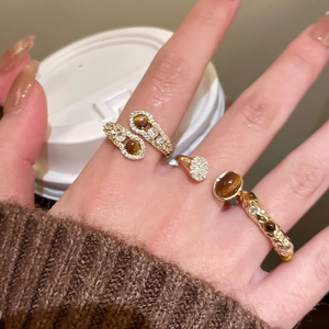 Detailed view of three-piece gold ring set with tiger eye stones and zircon on model hand