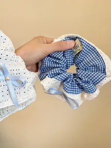 Detailed shot of blue checkered lace scrunchie with satin bow and a white pearl