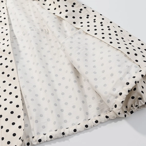 Detail shot of the black polka dot print and drawstring hem stitching on white fabric
