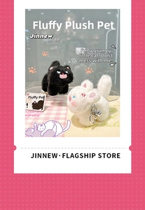 Detail of cute black and white fluffy kitten plush keychains with bells on a pink mat