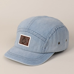 Detailopname van blauwe denim camperpet met bruine patch en metalen ringversiering