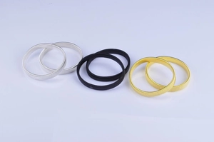 Three pairs of elastic metal armbands in silver, black, and gold colors on white background