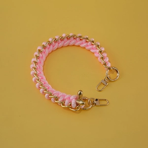 Detailed view of pink woven rope entwined with golden metal chain and lobster clasps