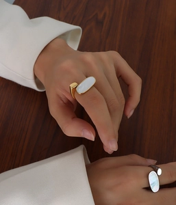 Gros plan d'une bague géométrique plaquée or 18 carats avec nacre blanche sur une main