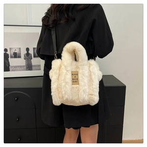 Detail of plush tote bag in cream white with black shoulder strap and gold metal buckles