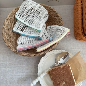 Detail van transparante mesh tasjes met contrasterende ritsen in een gevlochten mandje