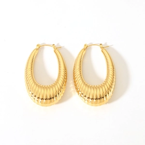 Détails macro des boucles d'oreilles créoles dorées en forme de U avec texture rainurée