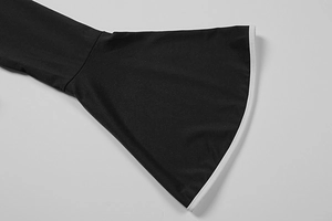 Detail of flared sleeve with contrast white piping on a black long sleeve shirt