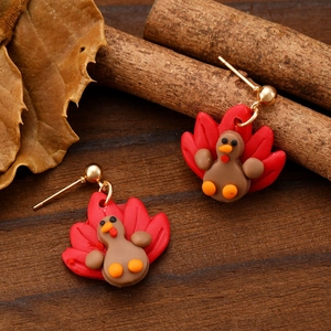 Macro detail of handmade polymer clay turkey earrings on rustic wooden background