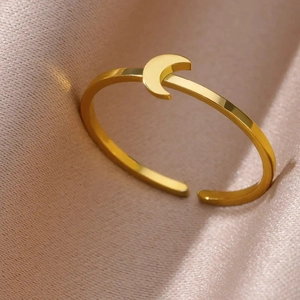 Macro detail of polished gold-plated stainless steel crescent moon open ring on silk