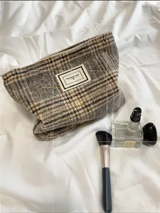 Detail of tweed plaid makeup bag with metal zipper on white fabric background
