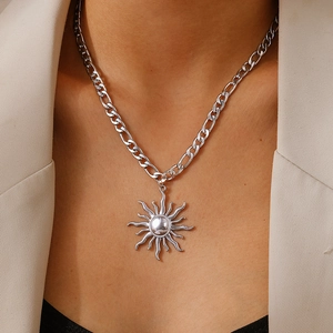 Gros plan du pendentif tournesol argenté sur une chaîne Figaro portée par un mannequin