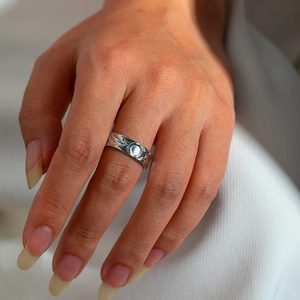 Detail of silver snake-style steel ring with textured round pattern on a model hand
