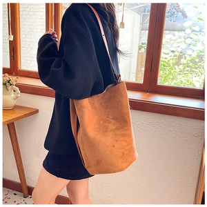 Close-up of brown suede bucket bag texture with long shoulder strap in soft light