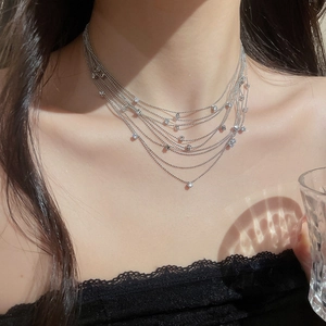 Detail of layered silver bead necklace with sparkling zircon pendants on model neck
