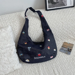 Detail of colorful embroidered patches and SOZAKKA logo on vintage denim crossbody tote bag