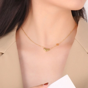 Gros plan d'un collier avec pendentif cœur doré minimaliste porté par un mannequin