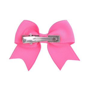 Detail of pink grosgrain ribbon bow with silver metal alligator clip on white background