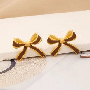 Detailed close-up of golden bow-shaped earrings with rich brown enamel inlay textures