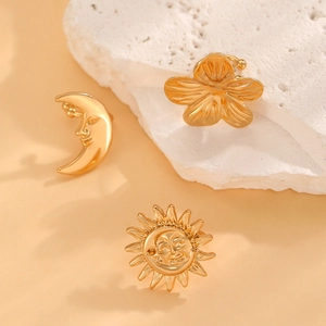 Detailed view of gold sun, moon, and flower ear cuffs set on a decorative mineral stone
