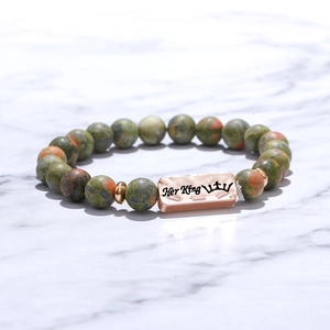 Macro detail of beaded stone bracelet with rose gold bar engraved Her King and crown