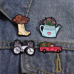 Détail de quatre broches en émail sur un jean avec des fleurs et un camion rétro