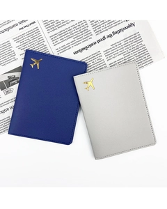 Detail of dark blue and grey leather passport covers with gold airplane logo on newspaper