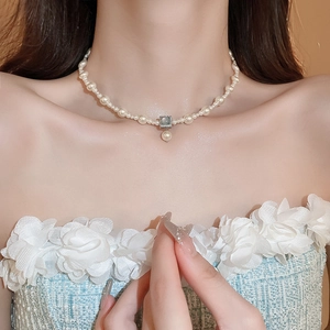 Close-up of gold-plated pearl necklace with a square gray gemstone pendant on a model