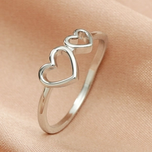 Close-up of interlocking silver double heart ring on champagne silk background