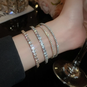 Close-up of elegant gold and silver bangles with sparkling zircon stones on a wrist