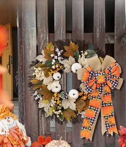 Detail of fall harvest wreath with maple leaves, white pumpkins, and orange plaid bow decor