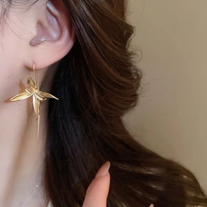 Close-up of elegant gold iris flower earrings worn by a model with a metallic finish
