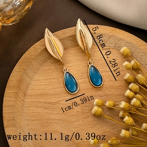 Detailed view of teardrop blue earrings with golden leaf accent and dimension specs