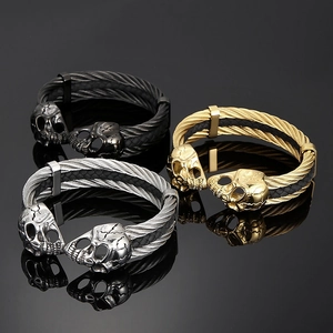 Detail of skull head cuffs in gold, silver, and black finish with braided steel cable wire